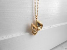 "A tiny golden teardrop locket hangs from a gold chain. Please select a length from the drop-down box. The locket measures 3/4\" x 3/8\". *We do not personalize nor insert pictures. The locket and chain are gold plated over brass, so it's recommended removing before showering, swimming, etc. to keep jewelry looking like new." Gold Teardrop Locket Jewelry, Gold Teardrop Pendant Charm Necklace As Gift, Gold Teardrop Locket Necklaces, Gold Teardrop Charm Necklace For Gift, Gold Teardrop Locket Necklace, Gold Teardrop Pendant Necklace For Keepsake, Teardrop Locket Necklace For Keepsake, Teardrop Locket Necklace Keepsake, Personalized Gold Teardrop Pendant Charm Necklace