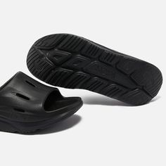 Created from EVA, Hoka One Ora slides feature oversized midsoles and sculpted soles for a futuristic appearance. They offer supreme comfort with a higher footbed of soft cushioning..Style Notes:.Hoka One Ora recovery slides.Black EVA.Designer logos, perforations, rubber soles.Size & Fit:.Slip on Textured Sole Slides For Streetwear, Sporty Slides With Textured Sole For Streetwear, Comfortable Slides With Textured Sole For Streetwear, Modern Slip-on Slides With Arch Support, Slides With Textured Sole And Round Toe For Streetwear, Outdoor Slide Sneakers With Cushioned Footbed, Streetwear Slides With Textured Sole And Round Toe, Modern Synthetic Slides For Streetwear, Modern Slides With Rubber Sole For Streetwear