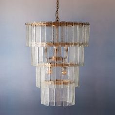 a glass chandelier hanging from a chain on a gray wall in a room