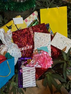 many wrapped gift bags are sitting on the ground next to a christmas tree and decorations