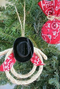 an ornament hanging from a christmas tree decorated with red bandana and black cowboy hat