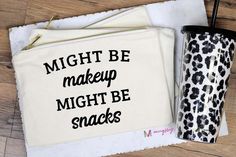 a white bag with the words might be makeup might be snakes on it next to a black and white leopard print cup