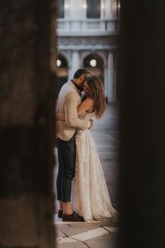 a bride and groom embracing each other in an archway