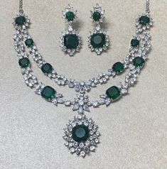 Emerald Necklace Set inspired by Sabyasachi Feturing semi precious green stone in white rhodium plating. Ideal to pair with your indi western sarees and gowns. Perfect gift for her. *𝐏𝐑𝐎𝐃𝐔𝐂𝐓 𝐃𝐄𝐓𝐀𝐈𝐋* * 𝐌𝐚𝐭𝐞𝐫𝐢𝐚𝐥: Brass * 𝐏𝐥𝐚𝐭𝐢𝐧𝐠: White Rhodium Plated * 𝐒𝐭𝐨𝐧𝐞: AAA-quality CZ Diamond & Emerald. *𝐃𝐈𝐌𝐄𝐍𝐒𝐈𝐎𝐍𝐒* *𝐍𝐞𝐜𝐤𝐥𝐚𝐜𝐞* * 𝐖𝐞𝐢𝐠𝐡𝐭: 56 gm * 𝐃𝐫𝐨𝐩 𝐋𝐞𝐧𝐠𝐭𝐡: 6.1 cm * 𝐖𝐢𝐝𝐭𝐡: 1.1 cm *𝐏𝐞𝐧𝐝𝐚𝐧𝐭* * 𝐋𝐞𝐧𝐠𝐭𝐡: 1.3 cm * 𝐖𝐢𝐝𝐭𝐡: 1.2 Luxury Gift Emerald Chandbali Necklace, Luxury Emerald Temple Necklace For Receptions, Luxury Gift Chandbali Emerald Necklace, Luxury Stone Work Necklaces For Eid, Luxury Green Emerald Necklace With Meenakari, Dazzling Green Emerald Necklace, Luxury Green Crystal Necklaces, Party Crystal Emerald Necklace Hand Set, Emerald Jewelry With Diamond Accents In Green