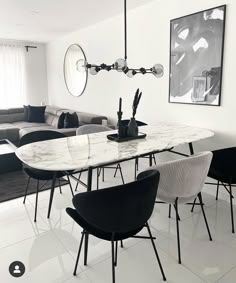 a dining room table with chairs and a couch in the back ground, next to a window