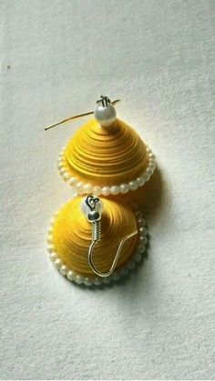 two yellow and white christmas ornaments sitting on top of a white sheet covered tablecloth