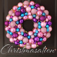 a pink and blue christmas ornament wreath hanging on a door with the words celebration written below it