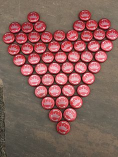 a heart made out of red buttons sitting on top of a cement floor next to a tree