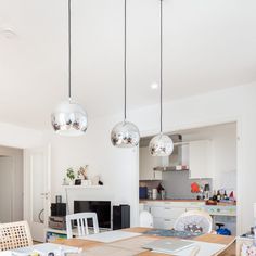 a kitchen table with chairs and lights hanging from it's ceiling in a home