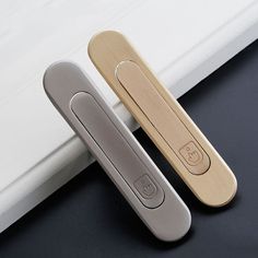 two wooden door handles sitting next to each other on a black surface with a white wall in the background