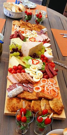 a wooden table topped with lots of different types of meats and cheeses on it