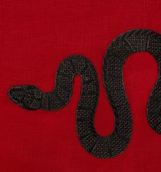 a black snake on a red background with the letter s in it's center