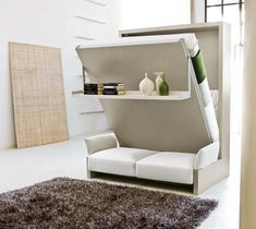 a living room with a white couch and book shelf on the wall next to a rug