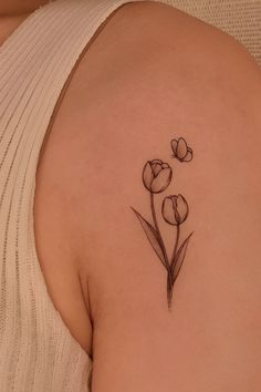 a woman with a tattoo on her shoulder and flowers in the middle of her arm