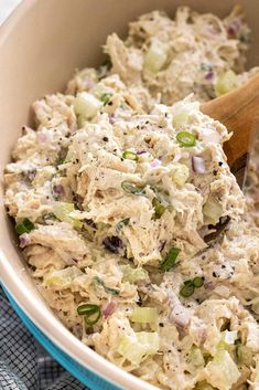 a bowl filled with chicken salad and a wooden spoon on top of a blue towel