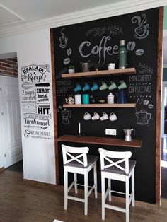 two white chairs sitting in front of a chalkboard wall with coffee writing on it