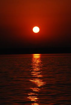 the sun is setting behind a boat in the water