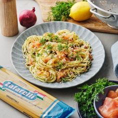 a plate of pasta with shrimp and parsley next to other ingredients on a table