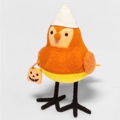 a stuffed bird is holding a small pumpkin