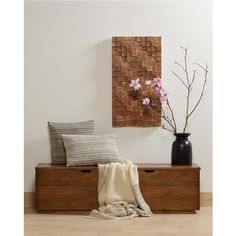 a wooden bench with two pillows on it and a vase filled with flowers next to it