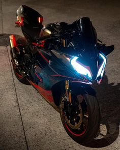 the motorcycle is parked on the side of the road at night with its lights on