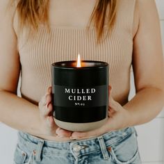 a woman holding a candle in her hands with the words cinnamon rolls written on it