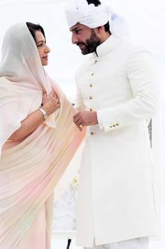 a man and woman standing next to each other in front of a white tent holding hands