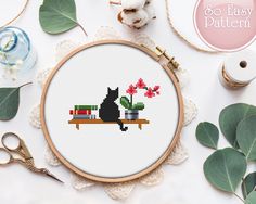 a cross stitch pattern with a black cat sitting on a bench next to some flowers