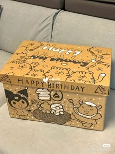 a birthday cake box sitting on top of a couch next to a remote control controller