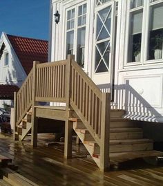 a wooden deck with steps leading up to a white house