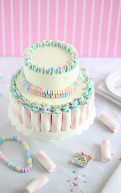 a three layer cake with pastel sprinkles and candy sticks on top