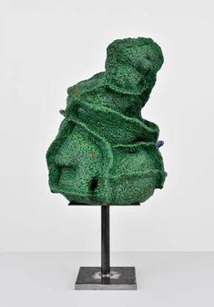 a green sculpture sitting on top of a metal stand