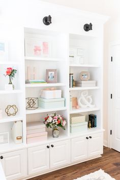 a white bookcase filled with lots of books on top of a hard wood floor