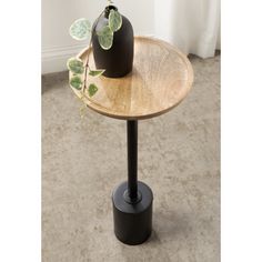 a wooden table with two black vases on it and some plants in the middle