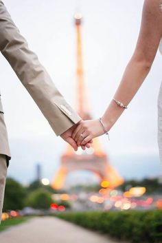 a bride and groom holding hands in front of the eiffel tower