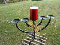 a red candle sitting on top of a metal candelabra in the grass