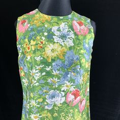 "Wonderful vintage Margaret Smith shift dress from the 1970's when her clothes were in Bonwit Teller and speciality shops across the country. Daisies, tulips and other colorful flowers on a green background. Soft easy care cotton blend fabric. Size 10 Bust: 35-36\" Waist: 34\" Hips: 34-35\" Length: 40.5\" Excellent condition no issues. There is an 1.5\" wide separate belt of the same fabric with this dress. This will be your go to dress for hot weather and resort vacations. Sale supports Vermont 1970s Sleeveless Floral Print Dress, Mid-century Floral Print Dress For Spring, 1970s Style Sleeveless Floral Print Dress, Mid-century Floral Print Spring Dress, Sleeveless Retro Print Dress For Garden Party, Sleeveless Dress With Retro Print For Garden Party, Sun Dress, Floral Sleeveless, Green Background