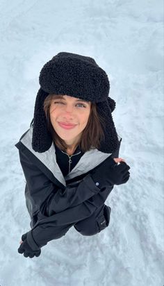 a woman wearing a black hat and jacket in the snow