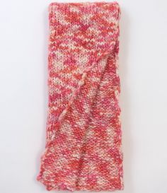 a pink and white scarf laying on top of a white table next to a wall