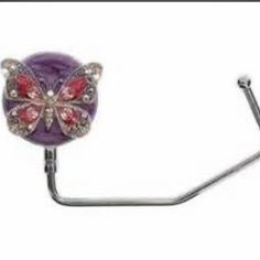 a metal hook with a purple butterfly on it's side and red crystals in the middle