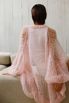 a woman sitting on top of a couch wearing a pink knitted cover over her body