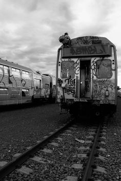 black and white photograph of two trains with graffiti on them