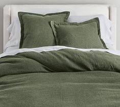 a bed with green sheets and pillows on it