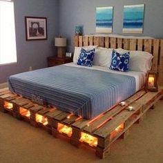 a bed made out of wooden pallets with candles on the bottom and lights underneath