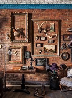 an old brick wall with pictures and deer heads hanging on it's sidewall