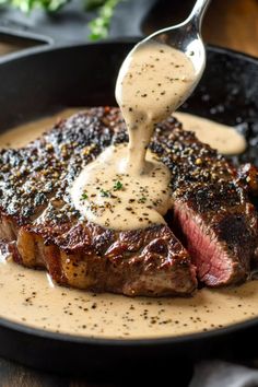 a steak being drizzled with sauce on top of it in a skillet