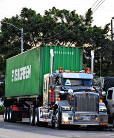 a semi truck driving down the road with a green container on it's back