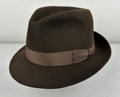 Lead the playboy high life in this 1950s fedora! Dark chocolate brown soft fur felt with a perfect pinch up front, wrapped in a brown grosgrain silk ribbon hatband, and finished with a raw edge. Leather inner hatband and unlined. Marked "Royal Stetson, Playboy model" and originally sold at Simpson's of Piccadilly, England. This hat is in great vintage condition appears virtually unworn with no holes, stains, or odors to note.    Marked Size: 7&1/4 UK, which translates to 7&3/8 US (I don't know why our sizing is one level off, but I can confirm that this is true to size as a US 7&3/8) Inner circumference: 23 & 1/8 Length (at longest point): 12.25" Inner Length: 8" Width (at widest point): 11" Inner Width: 6.5" Crown Height: 4.75" Brim Width: 2" Find our other vintage hep hats here: https:// Formal Brown Felt Hat With Short Brim, Formal Fitted Brown Fedora, Formal Brown Fedora Felt Hat, Brown Fedora Felt Hat For Formal Occasions, Brown Formal Fedora With Curved Brim, Formal Brown Fedora With Curved Brim, Brown Formal Fedora Hat, Formal Brown Fedora Hat, Formal Brown Fur Felt Fedora