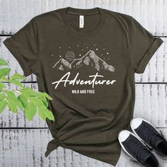 This Adventurer Wild And Free t-shirt is everything you've dreamed of and more. It feels soft and lightweight, with the right amount of stretch. It's comfortable and flattering for both men and women. Adventure Shirt, Wild And Free Shirt, Camp life shirt, hiking gift shirt * 100% combed and ring-spun cotton  * Heather colors contain polyester * Fabric weight: 4.2 oz (142 g/m2) * Pre-shrunk fabric * Side-seamed construction * Shoulder-to-shoulder taping * Unisex Size Pre-shrunk Relaxed Fit Adventure Shirt, Pre-shrunk Relaxed Fit Shirt For Adventure, Relaxed Fit Graphic Print Top For Adventure, Outdoor Slogan Crew Neck Top, Graphic Tee With Text Print For Adventure, Outdoor Slogan Tops With Crew Neck, Adventure Graphic Print Crew Neck Top, Short Sleeve Tops With Text Print For Adventure, Relaxed Fit Text Print Top For Outdoor Activities