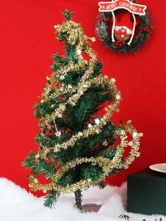 a small christmas tree in front of a red wall